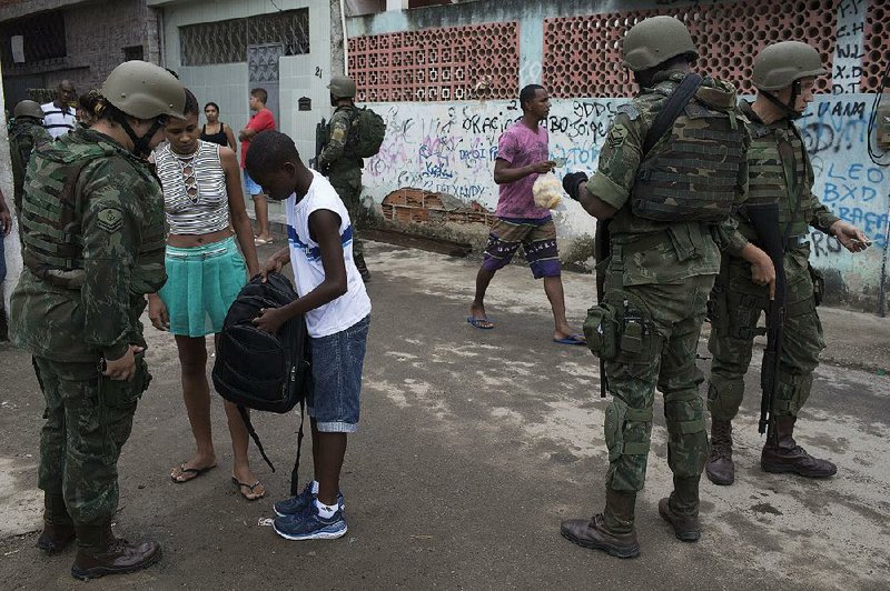 Brazilian marines search the backpack of a student Tuesday in a slum area during a crime sweep of Rio de Janeiro. 