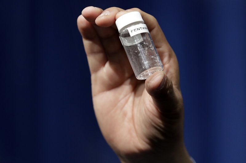 FILE - In this June 6, 2017 file photo, a reporter holds up an example of the amount of fentanyl that can be deadly after a news conference about deaths from fentanyl exposure, at DEA Headquarters in Arlington Va. Some large law enforcement agencies have recently abandoned the routine chemical field tests out of concern that officers could be exposed to opioids that can be absorbed through the skin or inhaled. Even a minute amount of the most potent drugs, such as fentanyl, can cause violent illness or death. (AP Photo/Jacquelyn Martin, File)