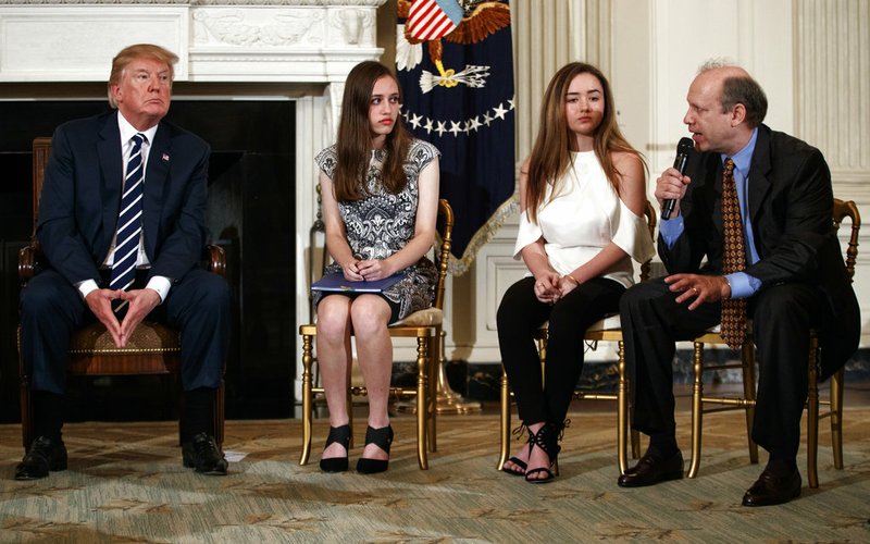 From left, President Donald Trump, Marjory Stoneman Douglas High School student students Carson Abt, and Ariana Klein, listen as Carson's father Frederick Abt, speaks during a listening session with high school students, teachers, and others in the State Dining Room of the White House in Washington, Wednesday, Feb. 21, 2018. In the aftermath of yet another mass school shooting, Trump says that if one of the victims, a football coach, had been armed “he would have shot and that would have been the end of it.” Revisiting an idea he raised in his campaign, Trump’s comments in favor of allowing teachers to be armed come as lawmakers in several states are wrestling with the idea, including in Florida, where the 17 most recent school shooting victims are being mourned.