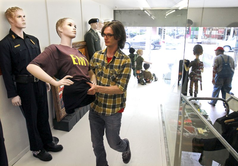 FILE PHOTO: In April 2014, Ian Darwin sets up mannequins in a display window of Bennett's Military Supply store at its new location at 6th and Main Street, just a few blocks up the street from its former location. The store has been on Main Street since 1870. 
