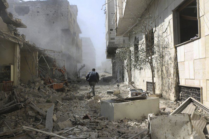 In this photo released on Thursday Feb. 22, 2018 which provided by the Syrian anti-government activist group Ghouta Media Center, which has been authenticated based on its contents and other AP reporting, shows a Syrian man runs between destroyed buildings which attacked during airstrikes and shelling by Syrian government forces, in Ghouta, a suburb of Damascus, Syria. (Ghouta Media Center via AP)