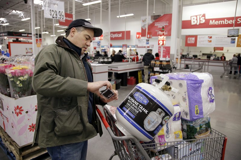 In this Tuesday, Feb. 13, 2018, photo, just before checking out, Tony D'Angelo uses the BJ's Express Scan app to scan in a propane tank he is purchasing at the BJ's Wholesale Club in Northborough, Mass. For customers, scanning as they go can be faster and make it simpler to keep track of spending. For stores, the big expansion of this technology coming this year costs less than installing more self-checkouts. 