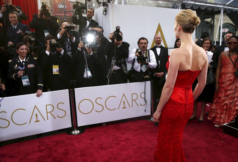 In this Feb. 22, 2015 file photo, actress Rosamund Pike arrives at the Oscars in Los Angeles. There are two paths on the Oscars red carpet: one for famous people, and one for everyone else. Stanchions and velvet ropes separate the recognizable from the not. Famous folks walk on the side of the carpet closest to the cameras and reporters, and stars often collide or share impromptu carpet greetings. 