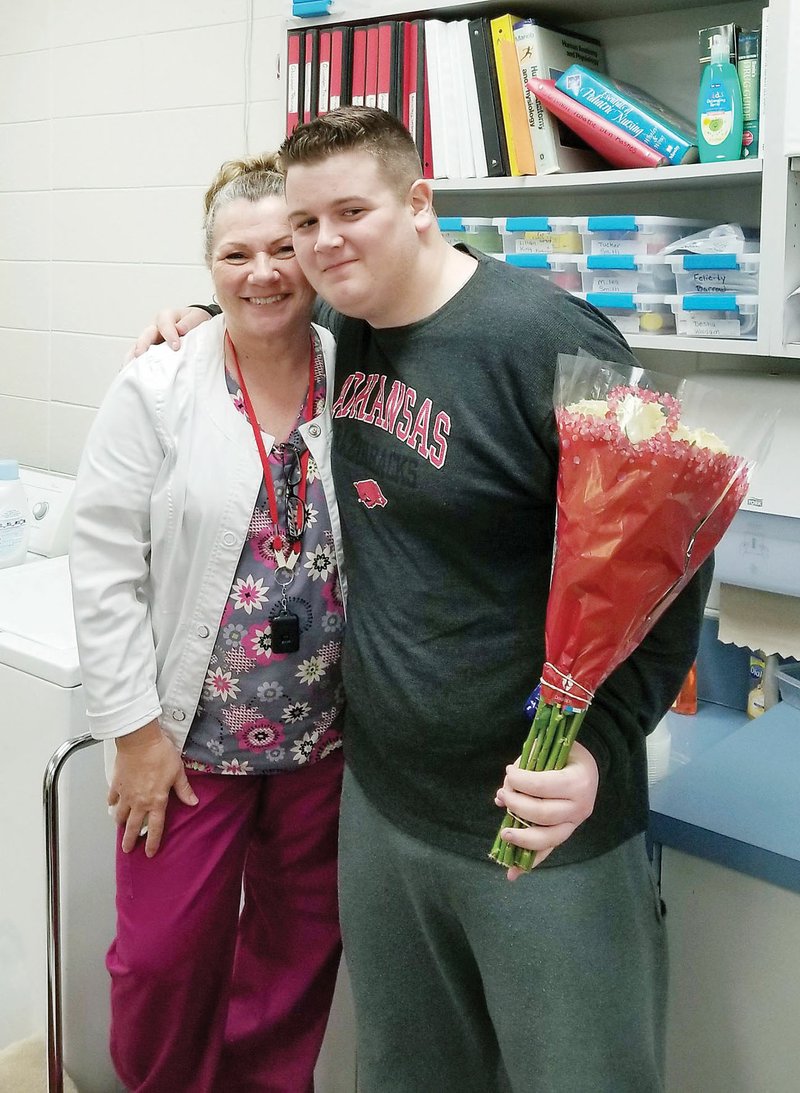 Rose Bud sophomore Joey Coughlin brings flowers to Jeannie Cook, the district’s school nurse, a week after she helped save his life after he collapsed in a classroom. Cook said Coughlin had no pulse, and she performed CPR on him and used an automatic external defibrillator until first responders arrived. Coughlin is back at school and “looks great,” Cook said.
