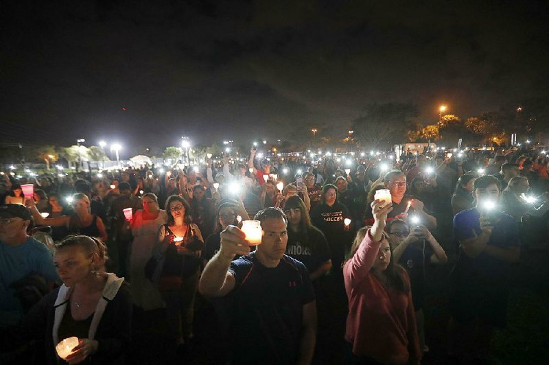People participate in a candlelight vigil Monday in memory of the 17 students and faculty members who were killed in the Feb. 14 mass shooting at Marjory Stoneman Douglas High School in Parkland, Fla. Nikolas Cruz, a former student, was charged with 17 counts of premeditated murder on Feb. 15.