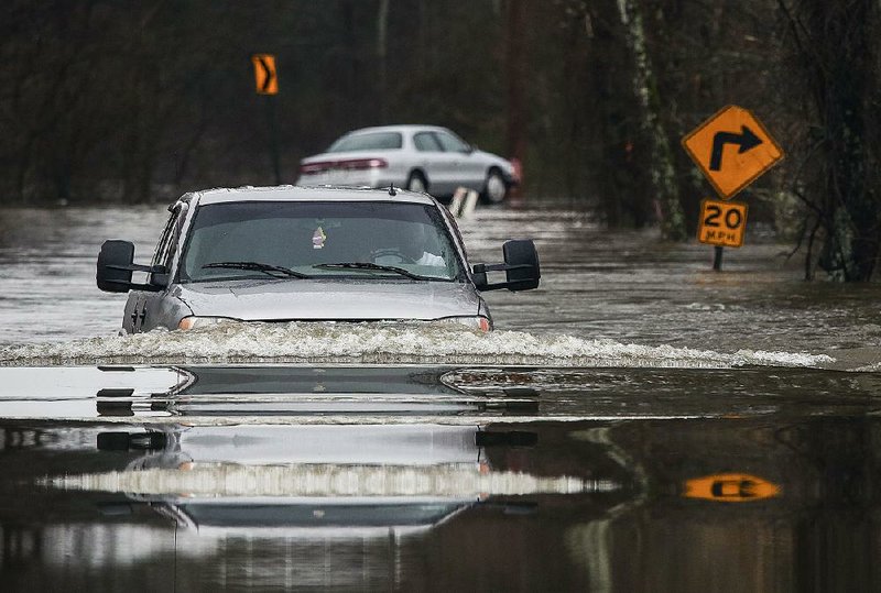 Nick Jackson of North Little Rock plows through high water Friday near Rixey and Barnder roads in North Little Rock. More rain is forecast today for much of Arkansas.