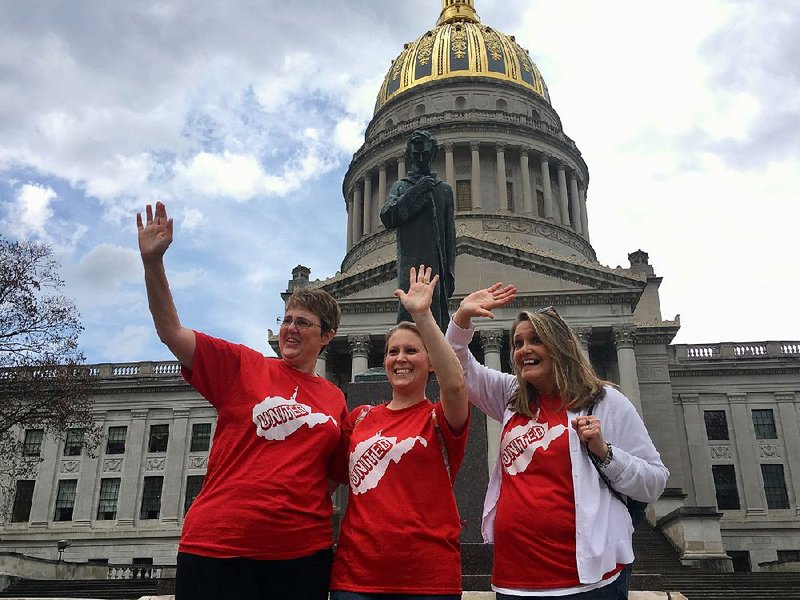 Striking teachers (from left) Michelle Myer, Holly O’Neil, and Suzanne Varner try to get the attention of passing motorists Friday outside the Capitol in Charleston, W.Va.