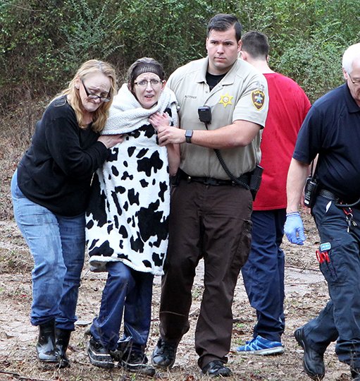 The Sentinel-Record/Richard Rasmussen RESCUED: Carol Morris, left, who lives nearby, and Garland County sheriff's Deputy Justin Butcher, right, help a woman to a waiting ambulance after she was rescued from the center of the Middle Branch of Gulpha Creek in the 1300 block of Millcreek Road on Friday.