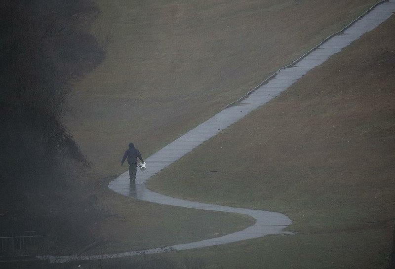 A fisherman heads to his car Saturday as rain intensifies at La Harpe View Park next to the Big Dam Bridge in Little Rock. 