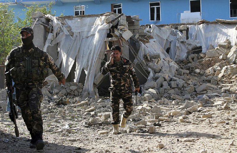 Security forces inspect the site of an explosion Saturday in Lashkar Gah, the capital of Afghanistan’s Helmand province. 