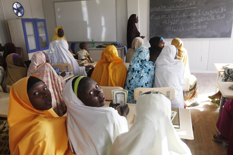 FILE- In this Monday, Dec. 7, 2015, file photo children displaced by Boko Haram during an attack on their villages receive lectures in a school in Maiduguri, Nigeria. About 50 young women remain missing Wednesday, Feb. 21, 2018, after Boko Haram extremists attacked a town in northern Nigeria that is home to a boarding school for girls, provoking fear that they may have met the same fate as those kidnapped from Chibok nearly four years ago. (AP Photo/Sunday Alamba, File)