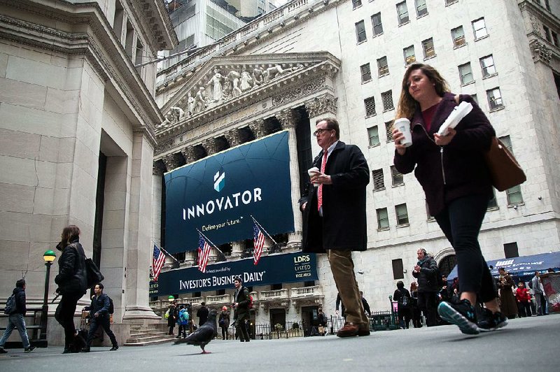 Pedestrians pass in front of Innovator Capital Management’s sign outside the New York Stock Exchange on Monday. U.S. stocks rose on renewed gains in Treasuries.