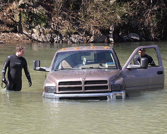 The Sentinel-Record/Richard Rasmussen UNDER WATER: Hot Springs Fire Department dive team members Nathan Blackstead, left, and Trey Hicks look over a Dodge Ram pickup truck that was discovered in the middle of Gulpha Creek near Essex Park Golf Course on Monday.