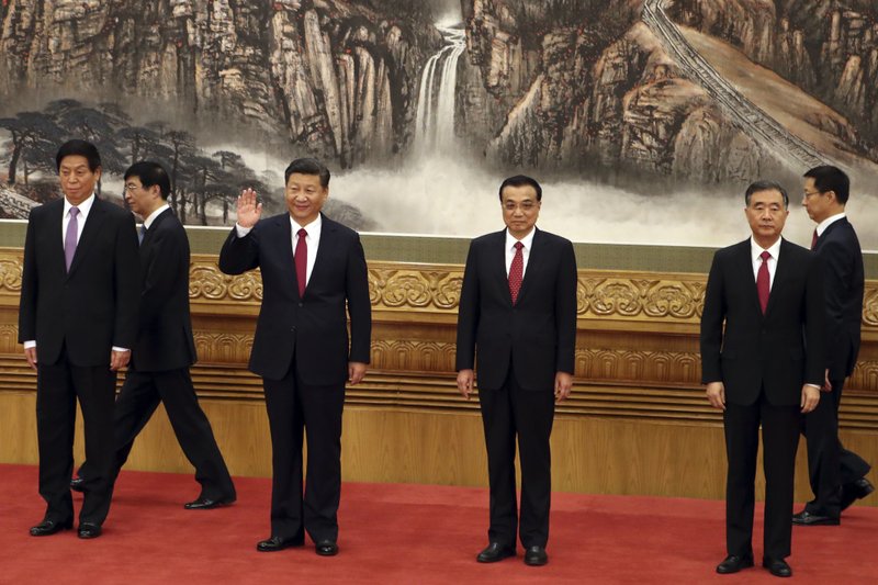 FILE - In this Oct 25, 2017, file photo, Chinese President Xi Jinping, third from left, waves near Chinese Premier Li Keqiang, third from right, as they walk in with other members of the Chinese Politburo Beijing's at the Great Hall of the People. On a proposal made public Sunday, Feb. 25, 2018, China's ruling Communist Party proposes removing a limit of two consecutive terms for the president and vice president. (AP Photo/Ng Han Guan, File)