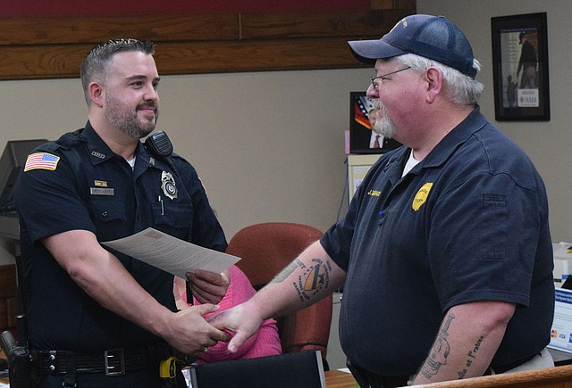 Westside Eagle Observer/MIKE ECKELS Officer Randy Deason, Decatur Police Department, receives congratulations from Chief Joe Savage during the Decatur City Council meeting at Decatur City Hall Feb. 15. Deason received a commendation for saving the life of a three-month-old baby who was choking and unresponsive Jan. 2.