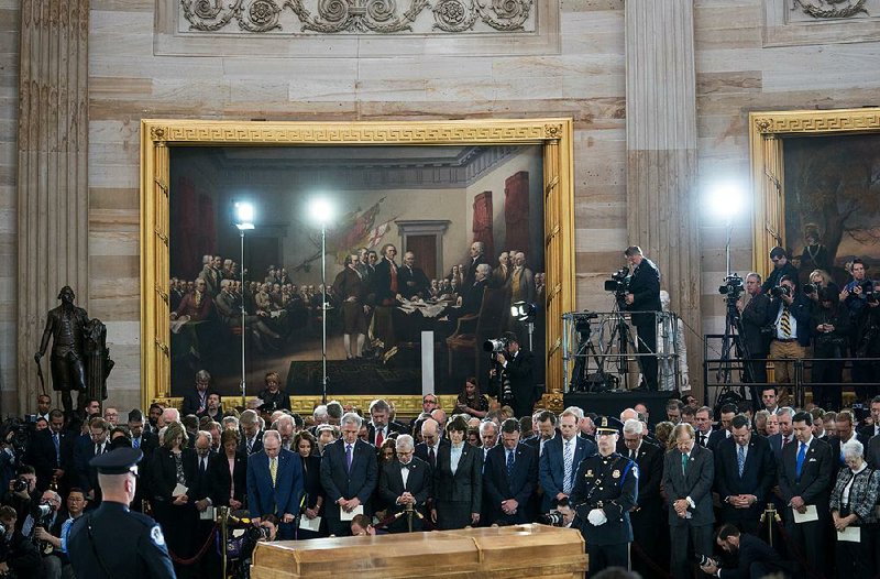 Republican and Democratic members of Congress bow in prayer Wednesday in the U.S. Capitol rotunda as they gather at the casket of the Rev. Billy Graham during a memorial service. 