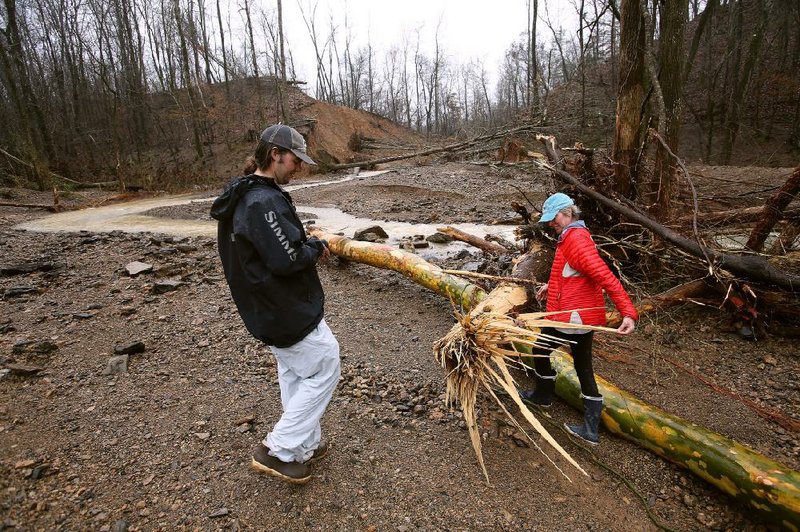Sandy Wilson of Pangburn and her son, Drew, look at the damage after water from a broken pond levee rushed past her home before dawn Wednesday. Flooding continues to cause problems around the state.