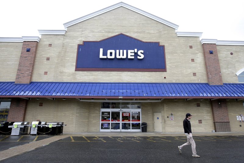 In this Friday, Feb. 23, 2018 photo a passer-by walks near an entrance to a Lowe's retail home improvement and appliance store, in Framingham, Mass.  (AP Photo/Steven Senne)