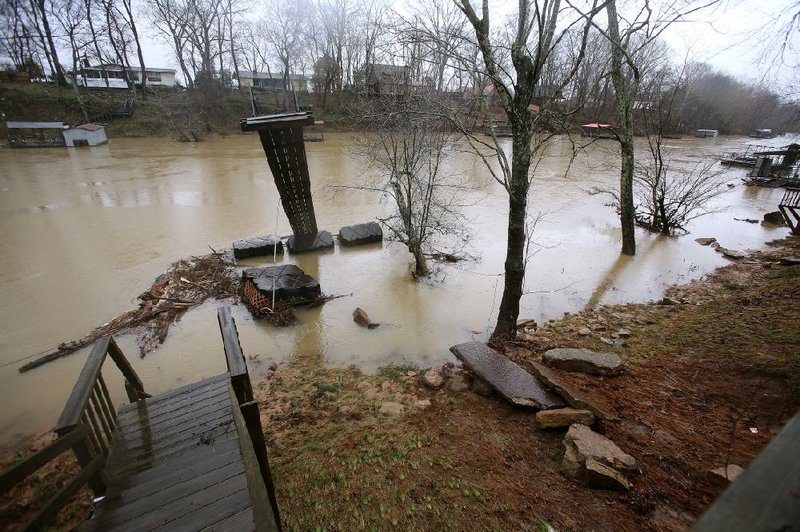 A boat dock sits flipped over in the Little Red River after it had been damaged during the rushing water from a culvert breaking on Wednesday, Feb. 28, 2018, in Pangburn. 