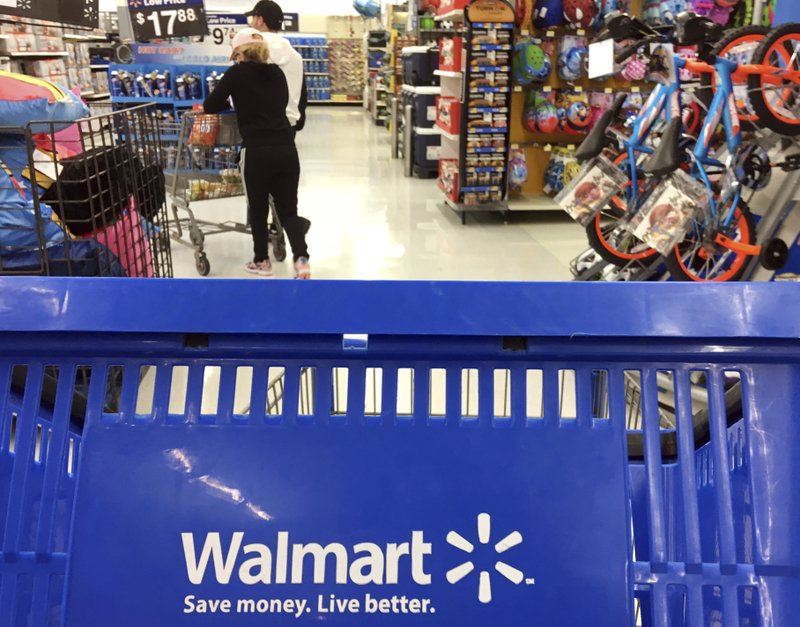 In this June 2017 file photo, customers shop for food at Walmart in Salem, N.H. Walmart says it will no longer sell firearms and ammunition to people younger than 21. The retailer's new policy comes after Dick's Sporting Goods announced earlier Wednesday that it would restrict the sale of firearms to those under 21 years old. It didn't mention ammunition. Walmart says the decision came after a review of its firearm sales policy in light of the mass shooting at a high school in Parkland, Florida. (AP Photo/Elise Amendola, File)