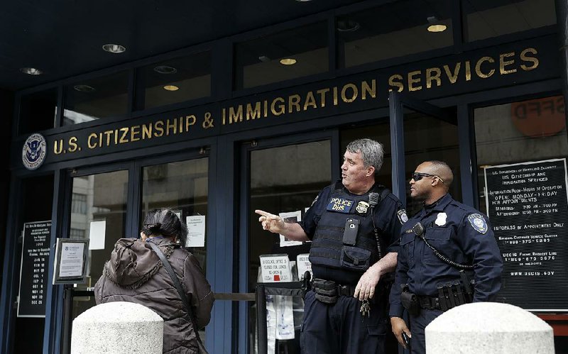 Police officers stand outside the Immigration and Customs Enforcement office in San Francisco this week. Recent immigration sweeps are frightening workers and harming California’s farm industry, a farmers group says.