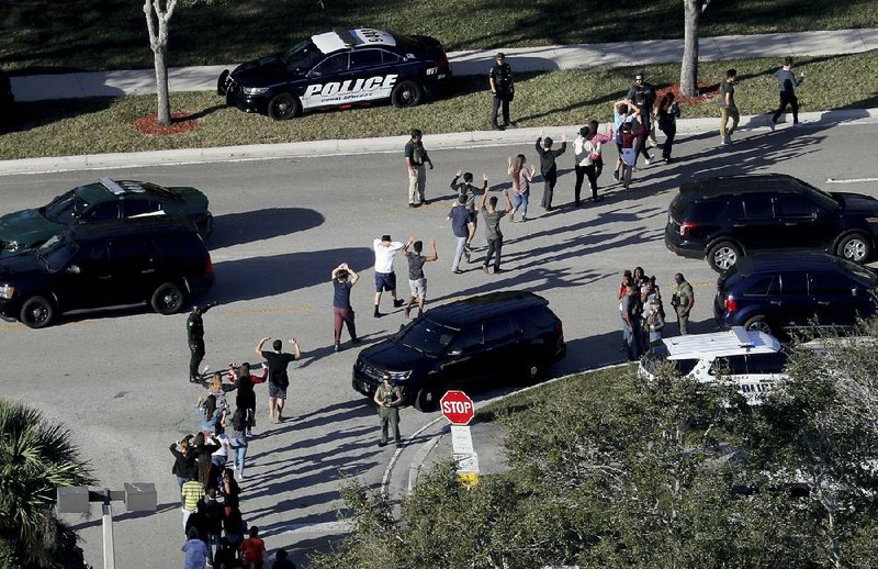 Police lead students away from Marjory Stoneman Douglas High School on Feb. 14 after a gunman opened fire inside, and an on-duty deputy failed to act. In Arkansas, law enforcement departments say they teach their officers that in such cases the first officer on the scene should immediately enter the building and confront the gunman.