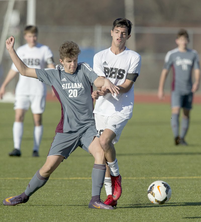 Ben Goff/NWA Democrat-Gazette Eli Simpson, No. 20, of Siloam Springs and Rodrigo Mouron of Bentonville collide Friday during the first round of the Northwest Arkansas Spring Soccer Classic tournament at the Tiger Athletic Complex in Bentonville. Siloam Springs defeated Bentonville 2-1.