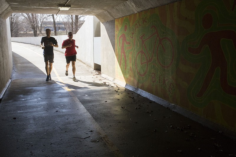 NWA Democrat-Gazette/CHARLIE KAIJO Joggers make their way through a tunnel on a bike path Feb. 15, 2018 at the Razorback Greenway in Bentonville.