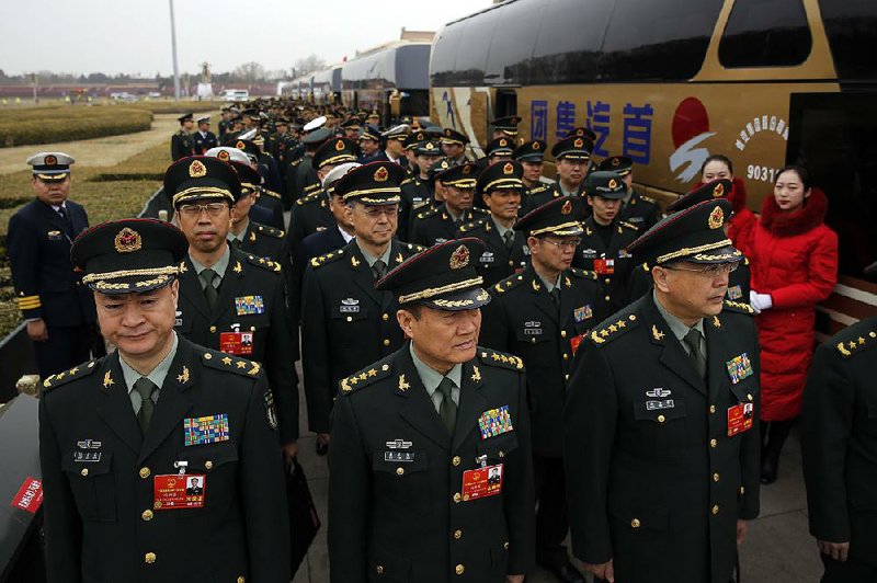 Delegates from China’s People’s Liberation Army line up as they arrive for a meeting at the Great Hall of the People in Beijing on Sunday ahead of today’s opening session of China’s National People’s Congress.