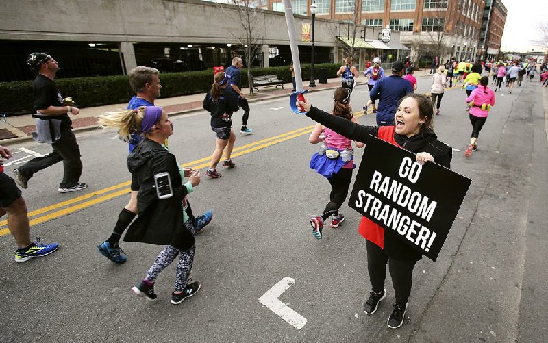 Maddie Qualls cheers on a group of runners on Third Street on Sunday during the 2018 Little Rock Marathon.