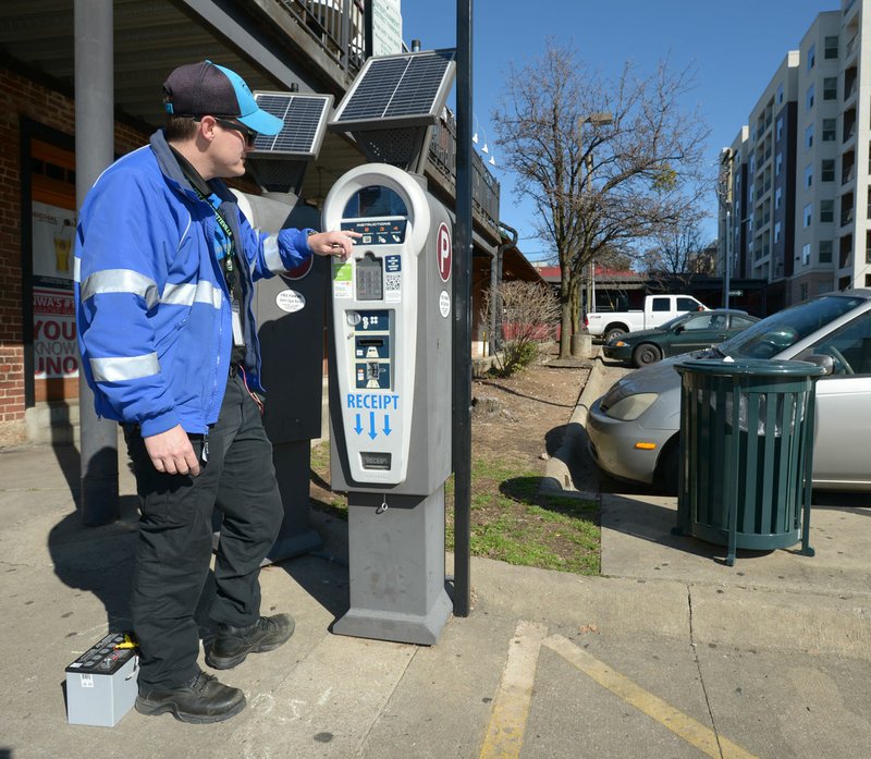 Luke Bouxsein, a parking enforcement officer with Fayetteville, changes a battery Friday on a parking pay station off West Avenue in Fayetteville. Consulting firm Nelson/Nygaard has completed a nearly 2-year study of parking downtown. On Tuesday, the City Council will discuss implementing the first phase of the study’s recommendations. One of the first steps of the recommended downtown parking plan is rebranding parking enforcement officers as customer servers, rather than ticket-writers.