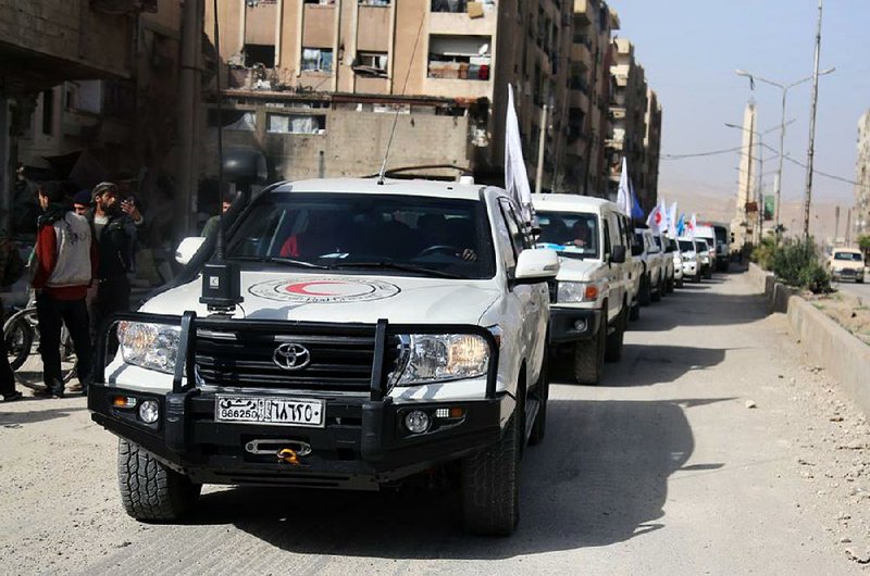 This photo released by the Syrian Red Crescent shows a convoy of Red Crescent vehicles arriving in Douma, eastern Ghouta, a suburb of Damascus, on Monday.