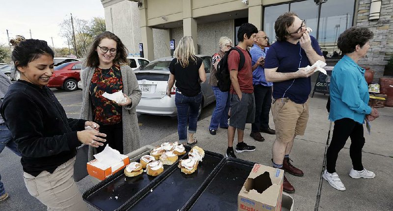 Lety Vargas (left) offers cinnamon rolls to voters as they wait in line at an Austin, Texas, grocery store that served as a polling site for Tuesday’s primary elections. 