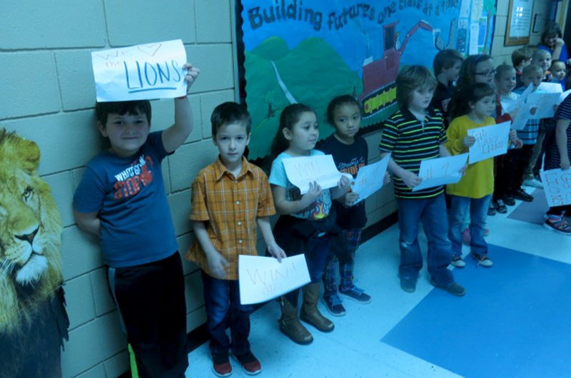 Westside Eagle Observer/SUSAN HOLLAND Students at Glenn Duffy Elementary School hold up signs they made to cheer on the Gravette Lady Lions when they visited the school Wednesday morning before their departure for the state basketball tournament. Students made the signs to show their support for the team at the sendoff organized by Taos Jones, assistant high school principal.