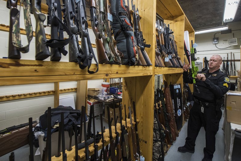 In this Feb. 27, 2018 photo, Sergeant Scott Pfeiffer, evidence room supervisor for the Westmoreland County Sheriff Department shows off a collection of guns that have been confiscated through court ordered seizure due to a protection from abuse order, inside the gun vault at the Westmoreland County Courthouse, in Greensburg, Pa. Confiscating firearms could easily be part of the job description for deputies on the second shift at the Westmoreland County Sheriff's Office. 