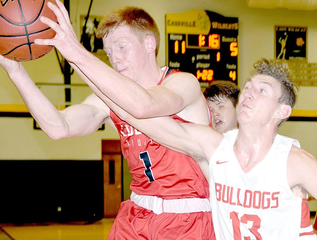 RICK PECK/SPECIAL TO MCDONALD COUNTY PRESS McDonald County's Blake Gravette takes a rebound away form Carl Junction's Will Bebee during the Mustangs' 58-41 loss on March 1 in the district semifinals at Cassville High School.