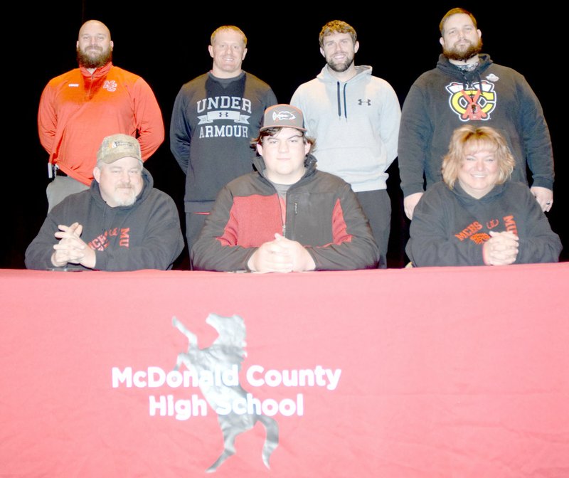 RICK PECK/SPECIAL TO MCDONALD COUNTY PRESS Trey Black (front row, center) recently signed a letter of intent to play football at Friends University in Wichita, Kan. Front row, left to right: Kelly Black (dad), Trey Black and Kristie Black (mom). Back row: MCHS football coaches Craig Collins, Sean McCullough, Kellen Hoover and Chris Kane.