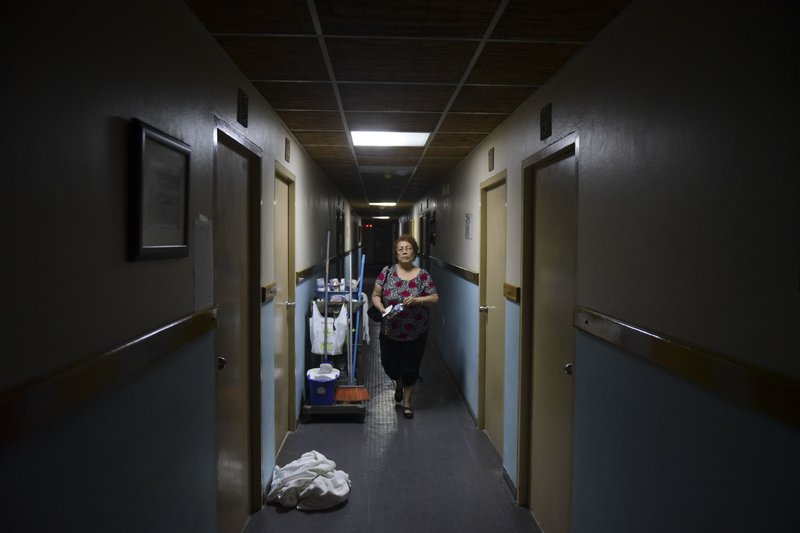 In this Monday, Feb. 26, 2018 photo, 69-year-old retiree Carmen Acosta walks down the corridor of the Boquemar hotel where she has taken refuge for months, after Hurricane Maria ripped the corrugated metal roof of her residence, in Cabo Rojo, Puerto Rico.(AP Photo/Carlos Giusti)