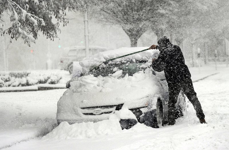 A man clears snow off of his car on State Street in Danbury, Conn., during Wednesday's snowstorm, March 7, 2018. Gov. Dannel P. Malloy has signed an order banning tractor-trailers and tandem trailers on Connecticut highways to help neighboring New York manage its traffic as highway conditions worsen because of the nor'easter. 