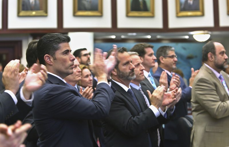 Rep. Jose Oliva, R- Miami Lakes, front, and other members of the Florida House, applaud Marjory Stoneman Douglas High School parent Andrew Pollack, who's daughter, Meadow Pollack, was killed in the school shooting, in Tallahassee, Fla., Wednesday, March 7, 2018. Oliva shepherd the bill through the House. 