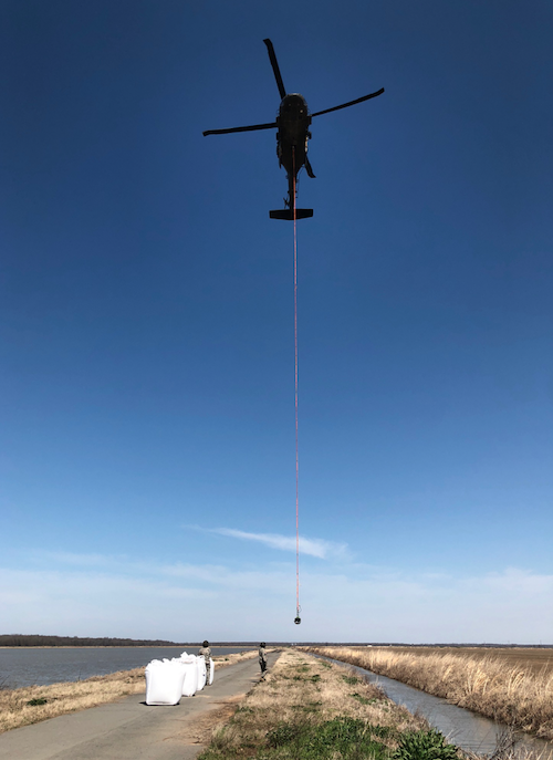 A National Guard helicopter drops sandbags to help manage flooding in Humnoke on Friday, March 9, 2018.