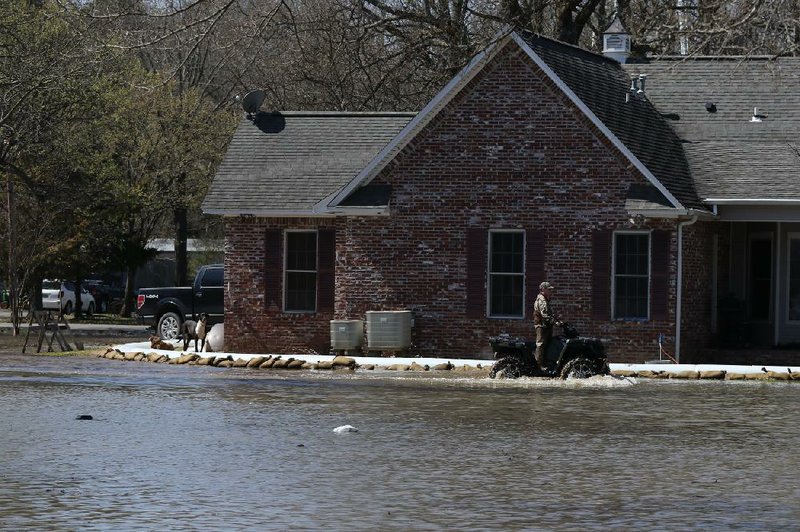 A resident drives through floodwaters Friday near a home in Humnoke, where a levee failure has inundated about 100 homes.