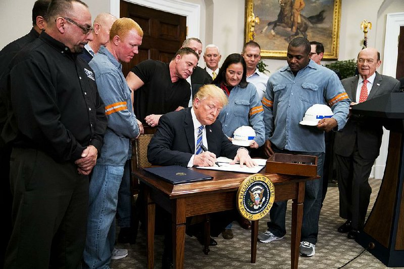 President Donald Trump, joined by steel workers, signs an order imposing sweeping new tariffs on imported steel and aluminum at the White House in Washington, March 8, 2018. Trump‚Äôs orders will raise levies on steel by 25 percent and aluminum by 10 percent but exclude for now Mexico and Canada. At far right is Commerce Secretary Wilbur Ross. (Doug Mills/The New York Times)