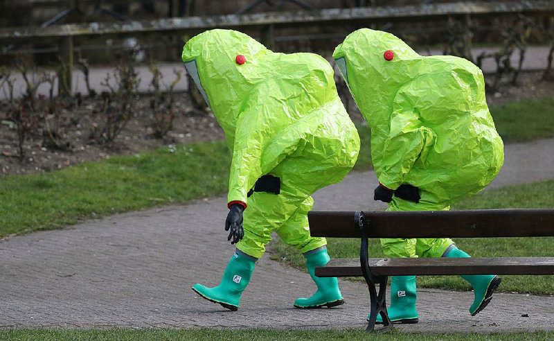 British crime-scene personnel in protective suits walk away from a park bench Thursday in Salisbury, England, the site of a suspected poisoning.