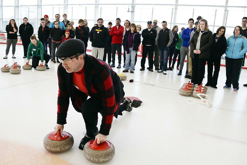 Club president Steve Taylor demonstrates how to perform a push off in the sport of curling at the Aksarben Curling Club in Omaha, Neb., in March. Interest in the sport has risen after the U.S. men’s team won gold medals in the Winter Olympics.  
