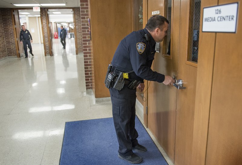 In this Feb. 23, 2018 photo, Resource Officer Tom Stumbo checks a door and tries to see inside the Media Center during a Lockdown exercise at Lincoln East High School in Lincoln, Neb. Some Nebraska teachers say they are considering responding to dangerous encounters in the wake of the deadly Florida shooting that killed 17 students and staff teachers. Several teachers interviewed say they appreciate their districts' security measures, despite wondering how they'd react in the classroom itself. They also say that they don't see arming teachers as a solution. 