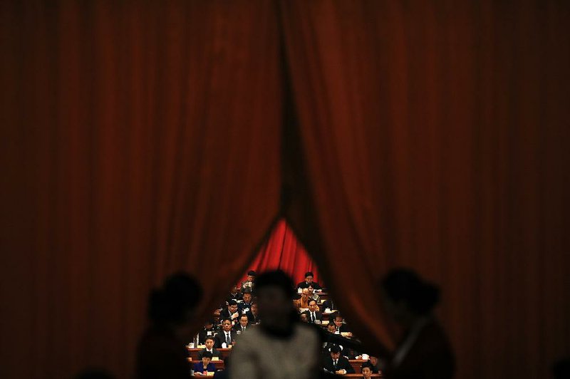 Attendants part a curtain Saturday for a delegate to China’s legislature in the Great Hall of the People in Beijing. The nearly 3,000 hand-picked delegates will vote today on abolishing term limits for the presidency, with passage all but certain.
