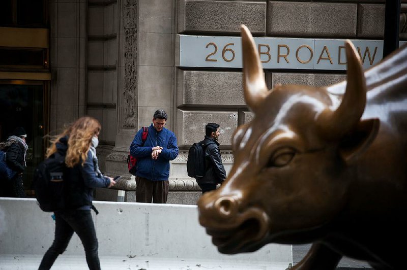 Pedestrians pass the Charging Bull statue near the New York Stock Exchange, where stocks rose sharply Friday after the Labor Department reported that the economy added 313,000 jobs in February, more than forecast.