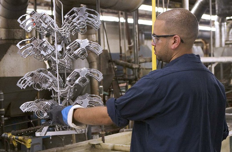 A worker guides a rack of snub-nosed revolver frames through several purifi cation baths at the Smith & Wesson plant in Springfi eld, Mass., in 2006. 