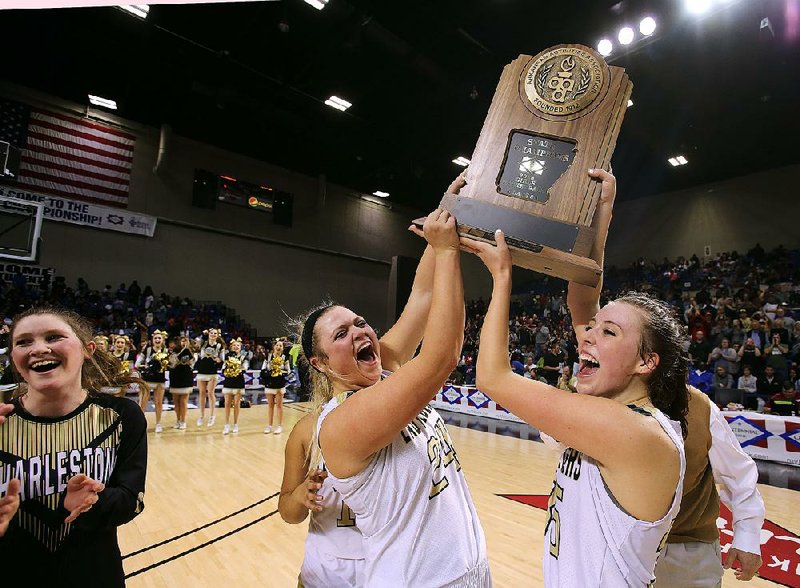 Charleston’s Lacey McKenzie (left) and Hattie Newhart hoist the Class 3A girls state championship trophy Friday after defeating Mountain View 67-59 at Bank of the Ozarks Arena in Hot Springs.